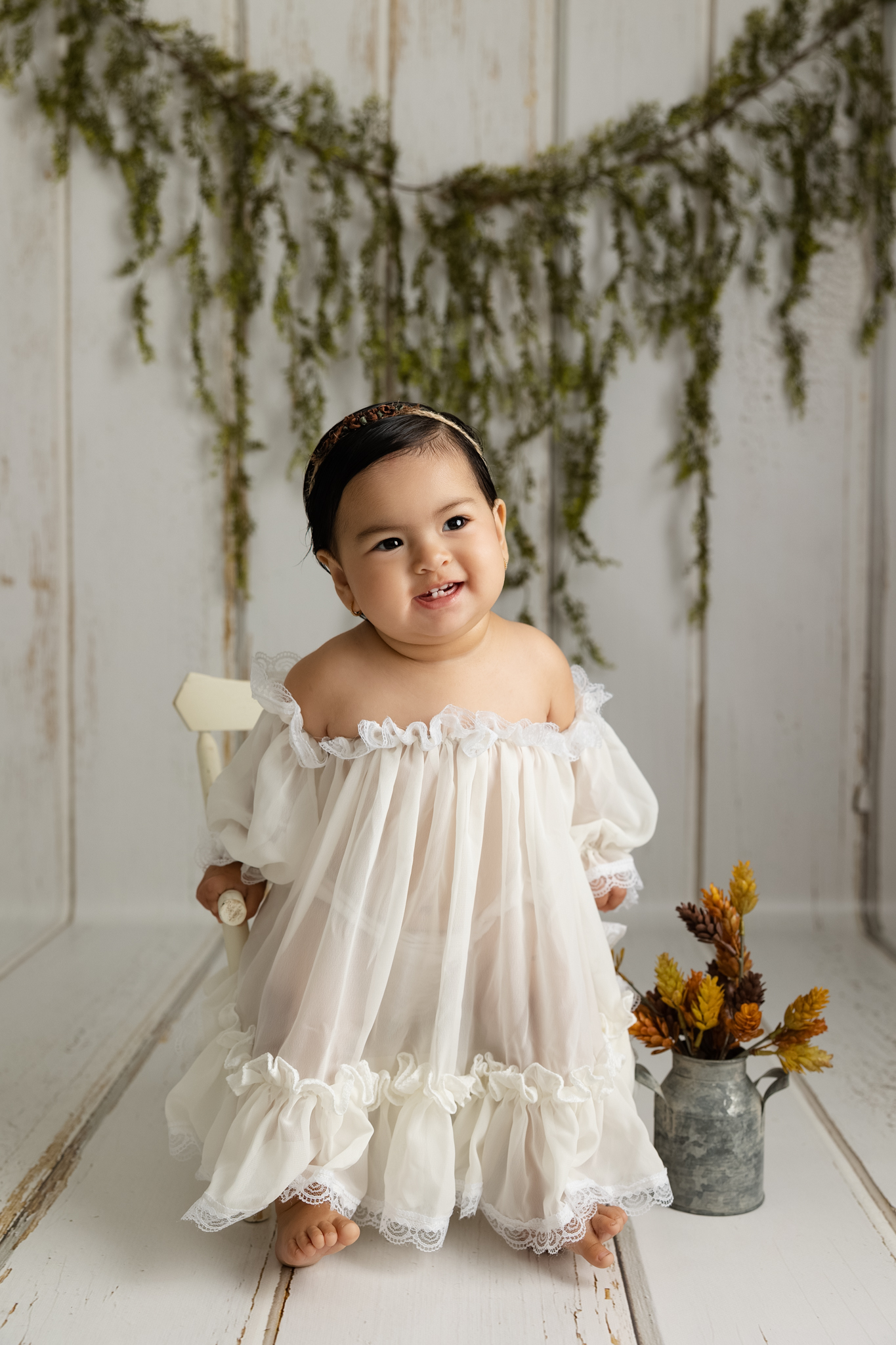 Smiling baby girl wearing a cream dress during a Fresno child photography milestone session