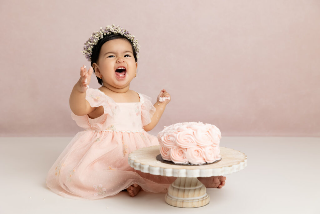 Fresno cake smash photographer capturing baby girl celebrating first birthday with pink cake