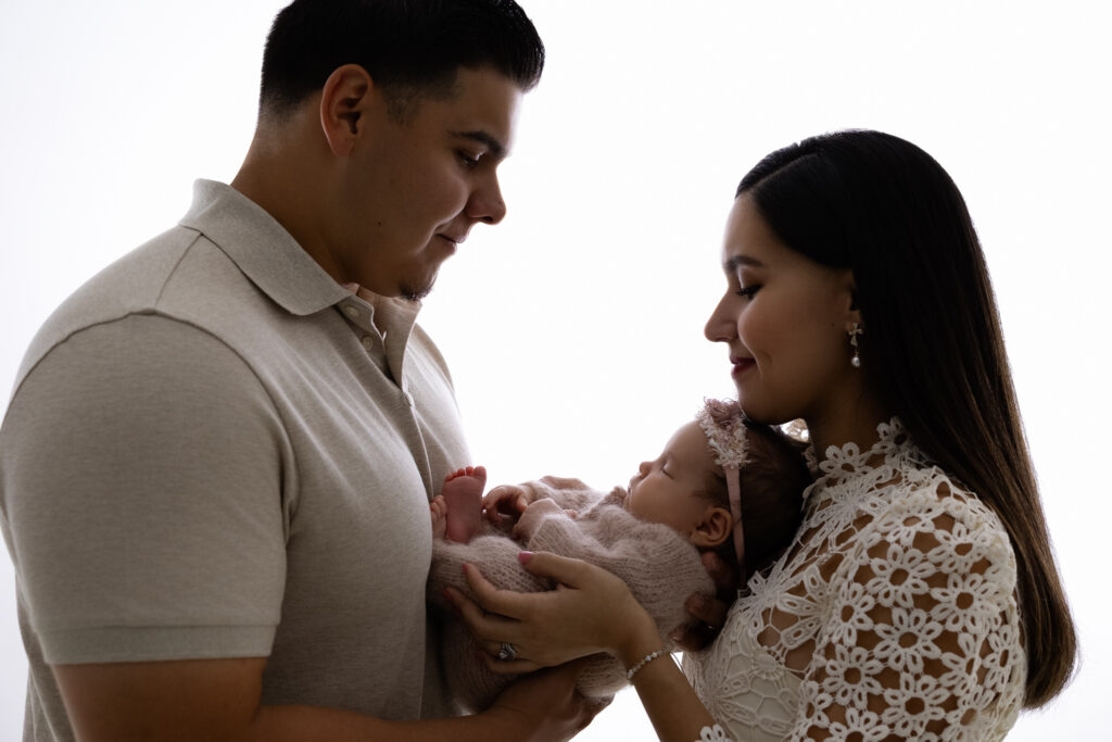 Fresno newborn photographer capturing parents holding their baby during in-studio newborn photography session