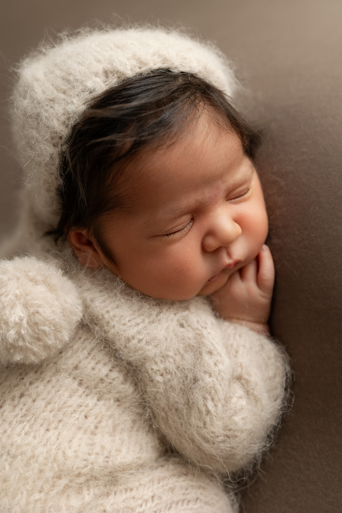 Sleeping newborn wrapped in a cream knit outfit during a Fresno newborn photography session